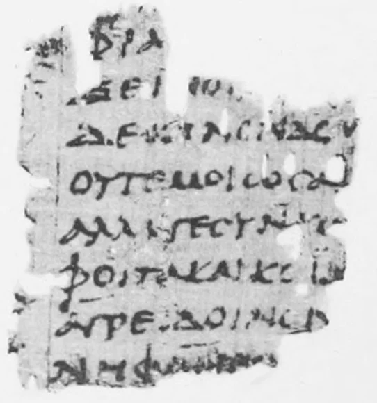Black-and-white photograph of a small papyrus scrap with seven lines of large Greek capitals.