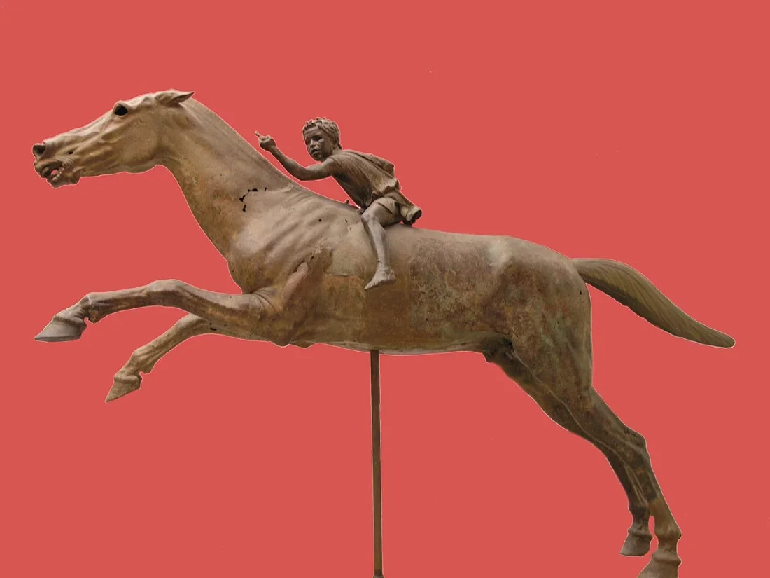 A bronze racehorse at full gallop with a small boy rider.