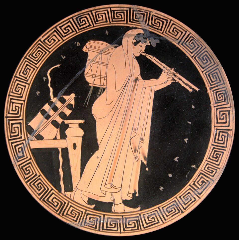 Red-figure cup interior: a figure playing the double pipes.