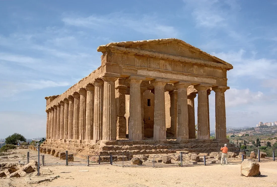 A well-preserved Doric temple in a dry landscape.
