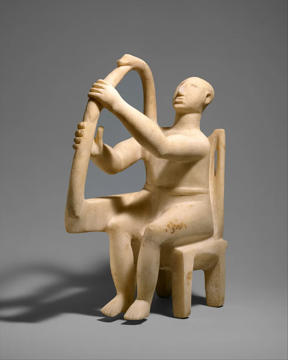 A small marble figure seated on a chair, head tilted back, holding a frame harp on its knee.