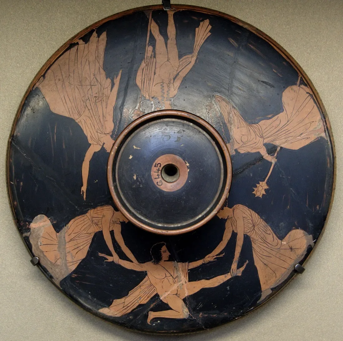A round lid painted with women pulling apart a man's body.