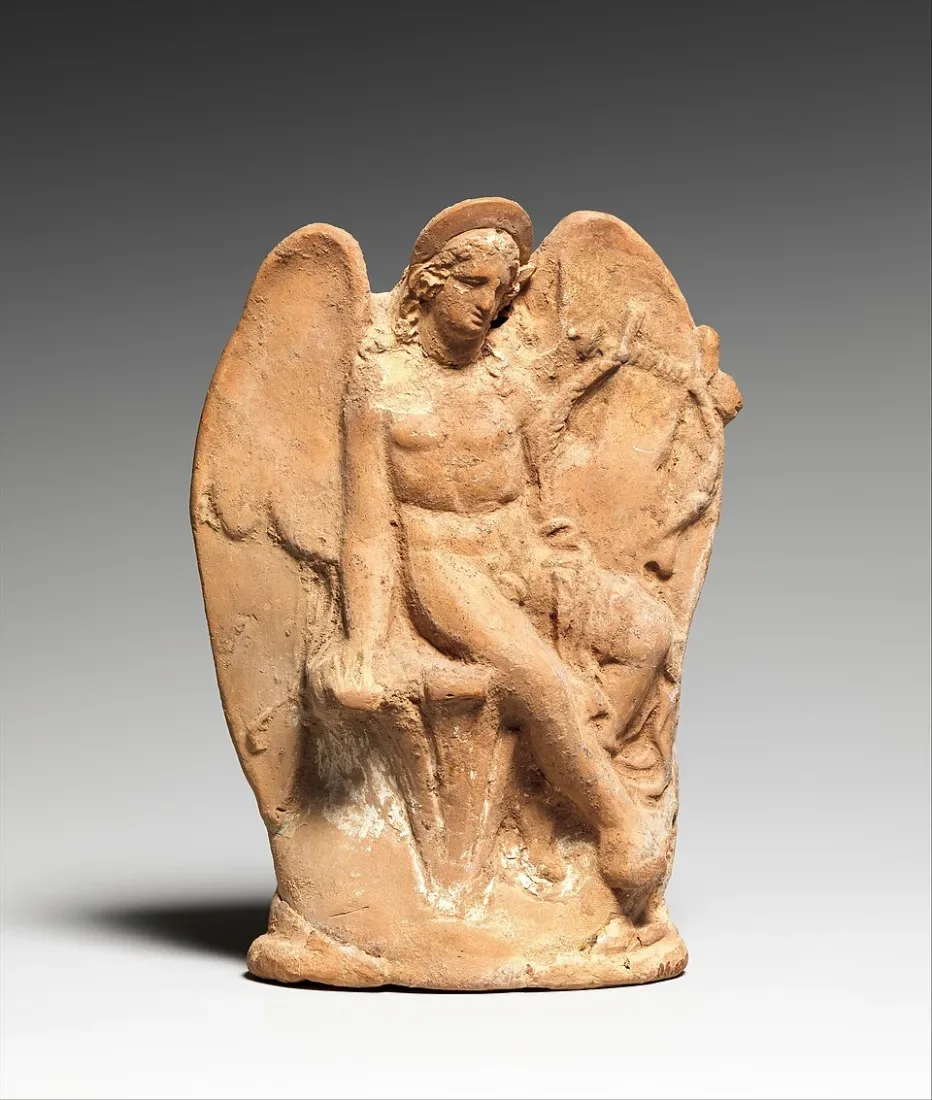 A small clay figure of a winged boy sitting on a rock.