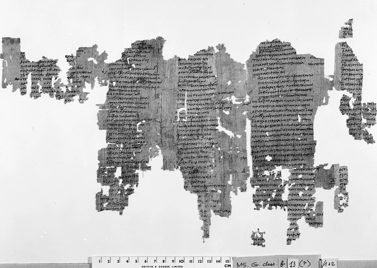 Black-and-white photograph of a large papyrus fragment with three columns of Greek script, much broken.