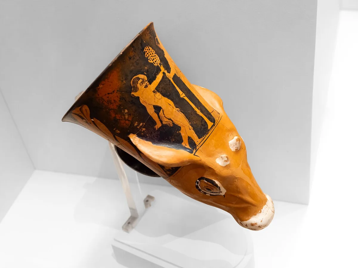 A drinking horn shaped as a fawn’s head; on its neck a satyr and a maenad hold a thyrsus.