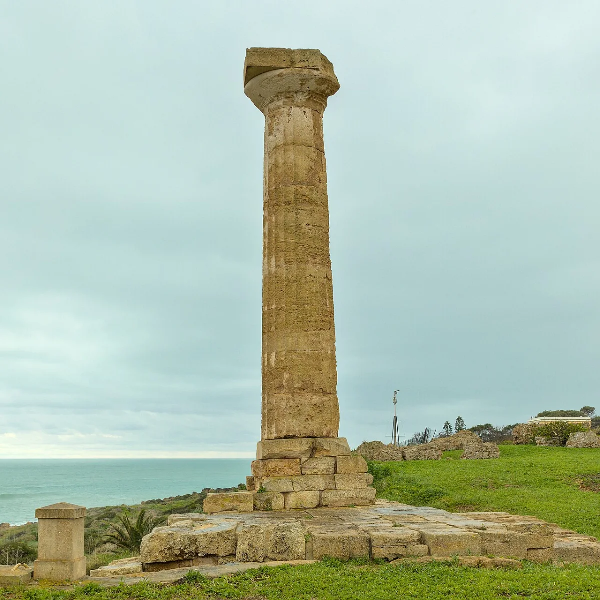 A single Doric column standing on a headland by the sea, the last of a temple.