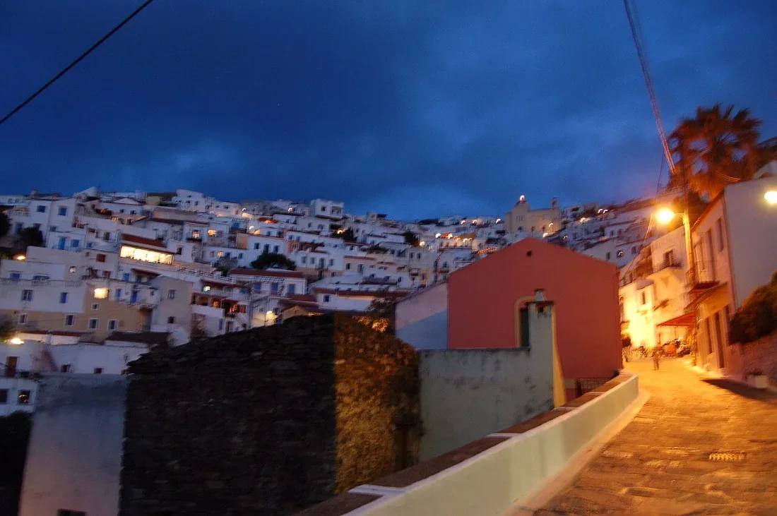 A white hill town at dusk, its houses climbing a slope.