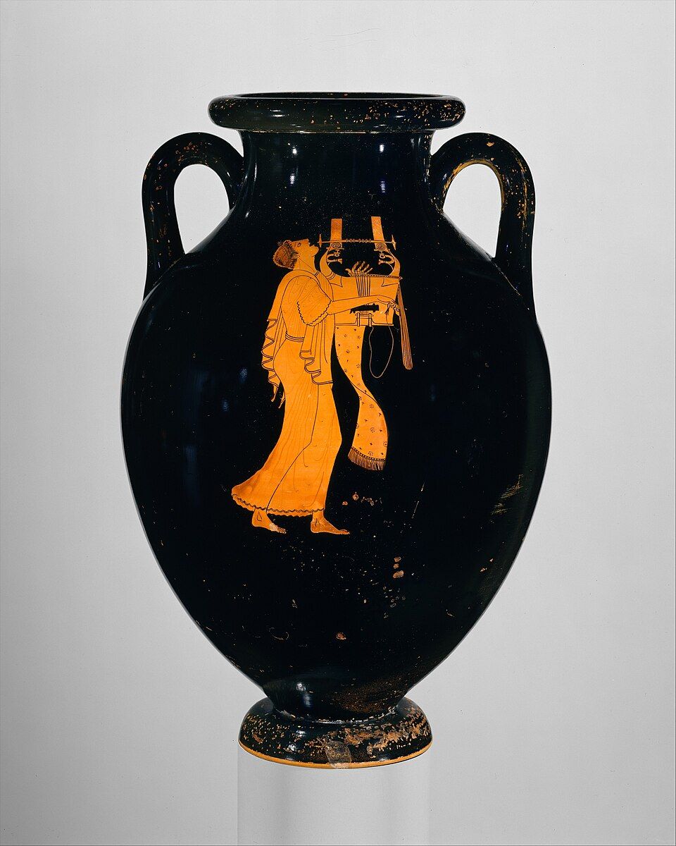 Black amphora with a single red figure of a young man in a long robe, head thrown back, playing a large kithara.