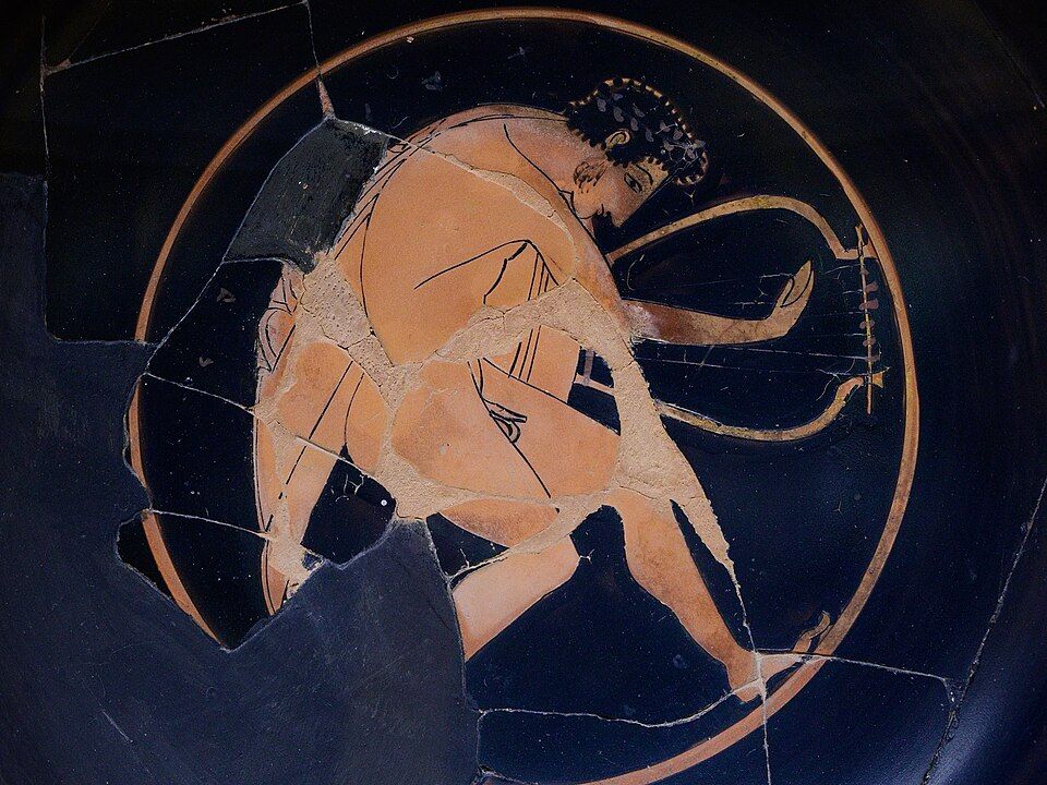 Red-figure cup interior: a reveller carrying a long-armed barbitos.