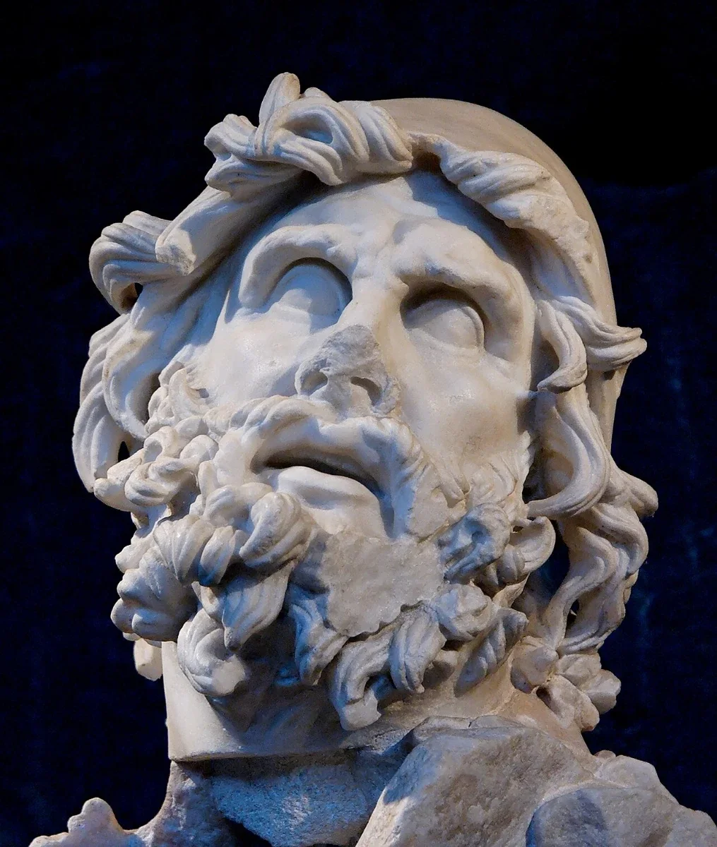 A marble head of a bearded man in a pointed cap, looking up.