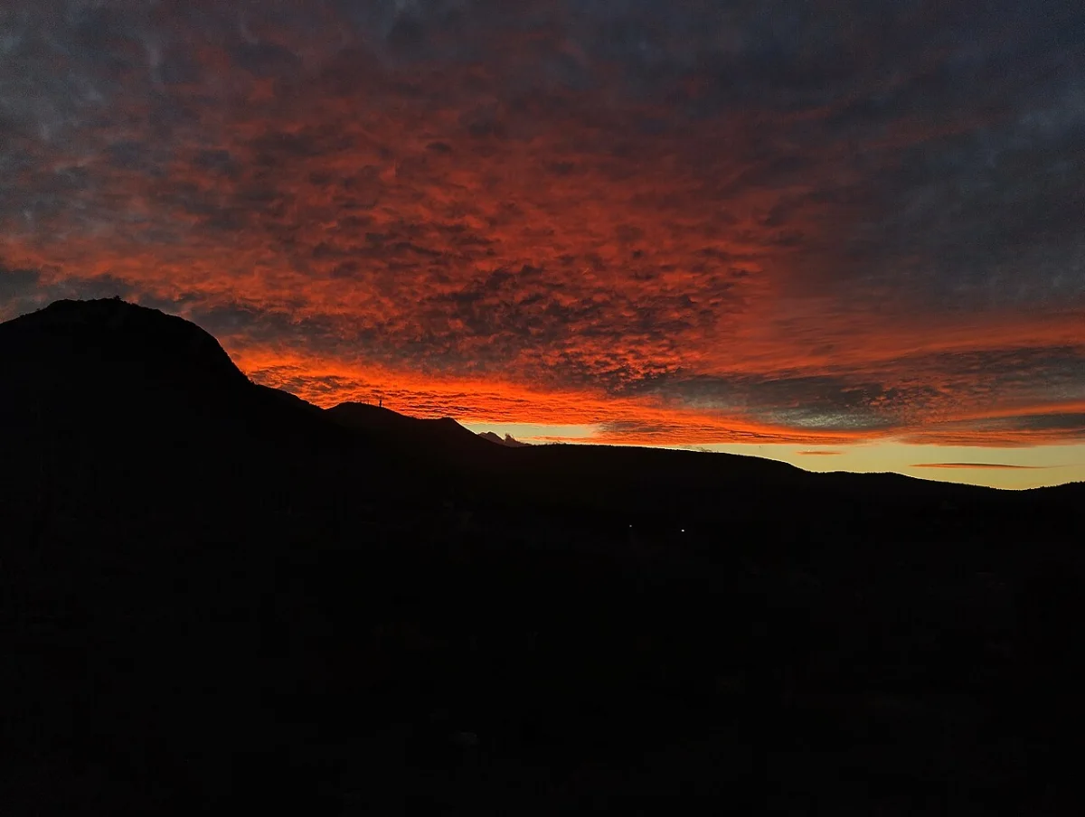 Red evening clouds above the dark outline of a mountain.