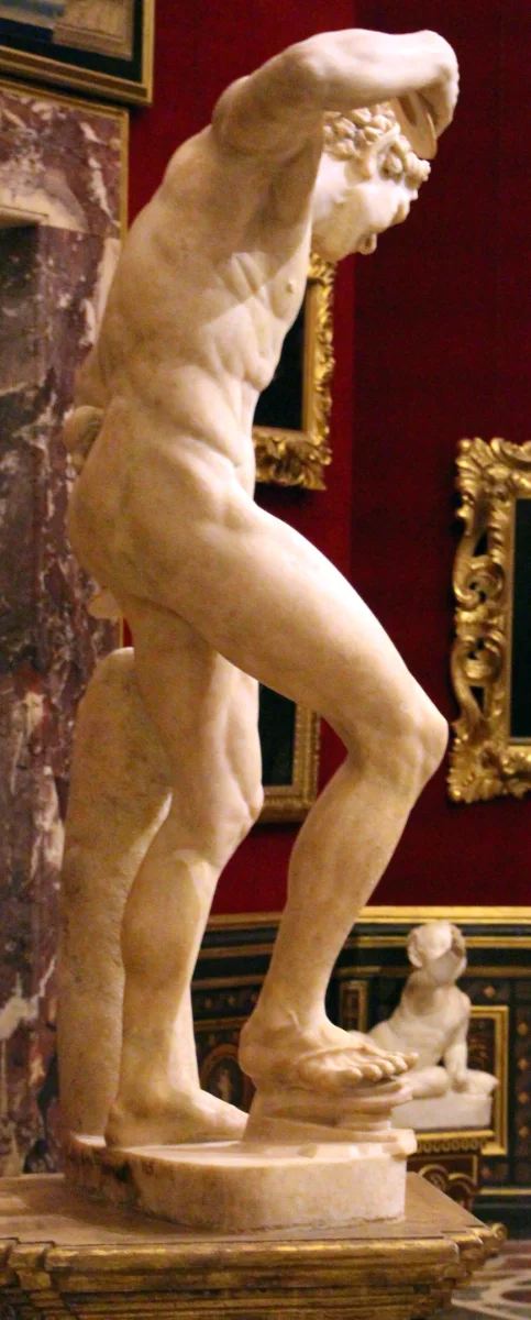 A marble statue of a dancing satyr, one foot on a hinged clapper-shoe, arms raised with cymbals.