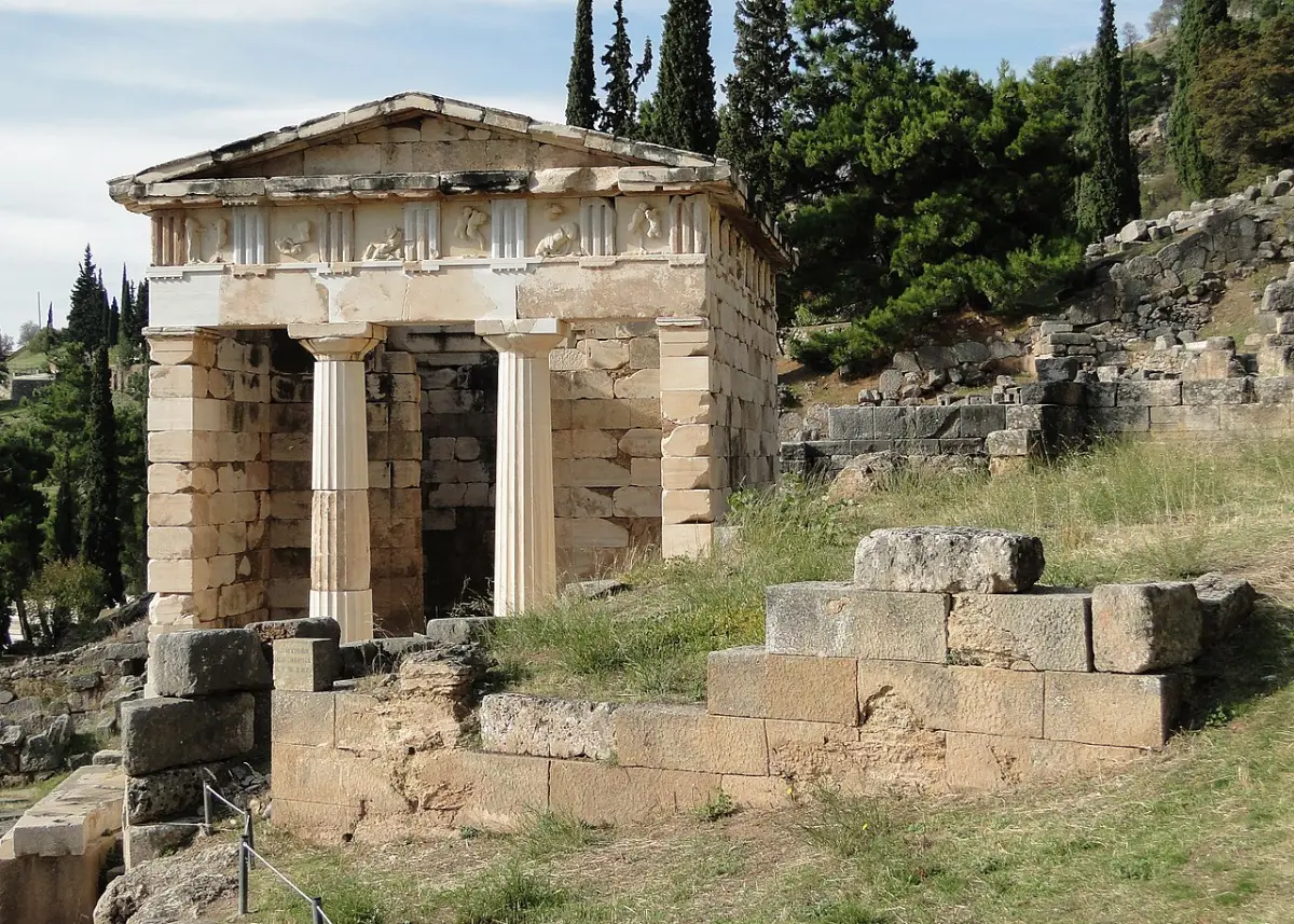 A small Doric marble building with two columns between the side walls, standing on a terrace among ruins and cypresses.