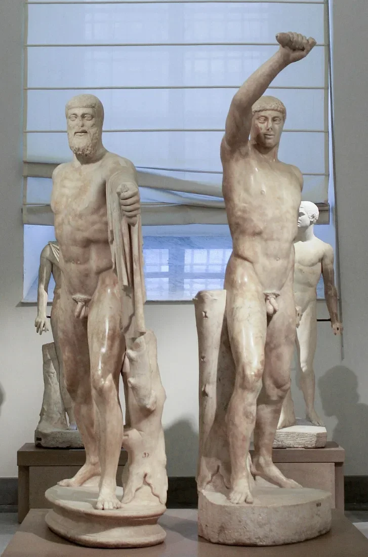Two marble statues of striding men, one raising his arm to strike.